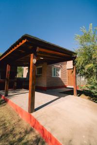 a wooden pavilion in front of a brick building at Cabañas Entre Campos in Los Reartes