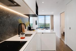 a kitchen with white cabinets and a large window at Punthill Ivanhoe in Melbourne +14 photos