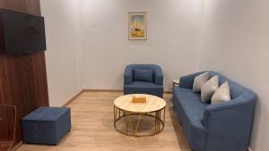 a living room with a blue couch and two chairs at Areen Almatar Serviced Apartments شقق ارين المطار للشقق المخدومة in Jeddah