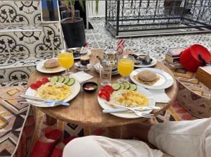 a table with plates of breakfast food and orange juice at Dar Skouri 51 in Marrakesh