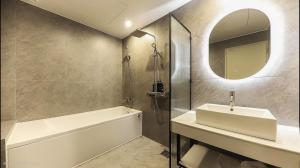 a bathroom with a sink and a tub and a mirror at Hotel RIL in Gwangju