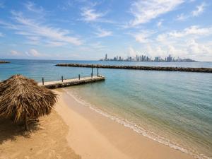 a beach with a pier and a city in the background at Tiny Village Cartagena Boutique Resort in Tierra Bomba