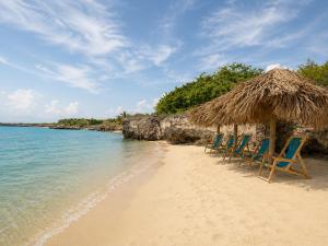 a group of chairs on a beach with a straw umbrella at Tiny Village Cartagena Boutique Resort in Tierra Bomba