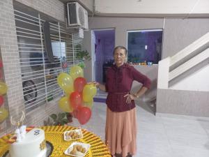 a woman standing in front of a table with balloons at Maktub Estadia e recepções in Paulista