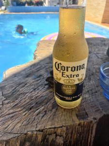 a bottle of corona beer sitting on a table next to a pool at Maktub Estadia e recepções in Paulista