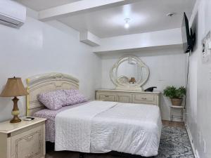 a white bedroom with a bed and a mirror at 2265 Bruckner Blvd Apartments in Bronx