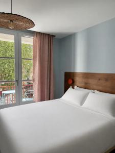 a bedroom with a white bed and a window at Hôtel Le Voltaire in Arles
