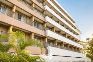 an apartment building with balconies and palm trees at Studio com Garagem e Acessibilidade | Granja Viana in Taboão da Serra
