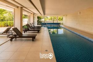 a swimming pool with lounge chairs in a building at Studio com Garagem e Acessibilidade | Granja Viana in Taboão da Serra