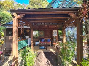a wooden pergola with a living room in a garden at Bali Haven in Coromandel Town