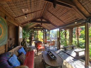 an outdoor living room of a house with a table and chairs at Bali Haven in Coromandel Town