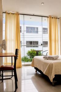 a bedroom with a bed and a desk and a window at Hotel Inkayacu in Paracas