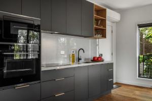 a kitchen with gray cabinets and a black microwave at Istana Indulge in Hepburn Springs +26 photos