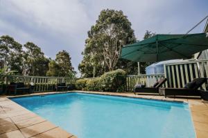 a swimming pool with a green umbrella and chairs at Istana Lodge in Musk Vale