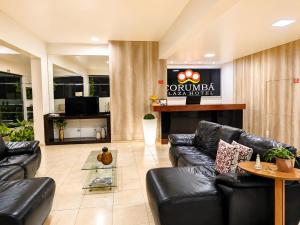 a lobby with black leather couches and a television at Corumbá Plaza Hotel in Luziânia