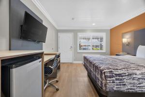 a hotel room with a bed with a desk and a television at Padre Oaks in Monterey +37 photos