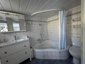 a bathroom with a tub and a toilet and a sink at Emmis-Ferienhaus in Dörpling +23 photos