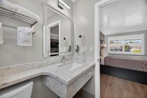 a white bathroom with a sink and a bed at Padre Oaks in Monterey