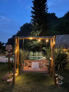 a wooden swing with lights in a garden at night at ALMAH GLAMPING in Cali