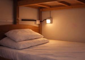a bed with a white pillow in a room at Armorial Hostel in João Pessoa