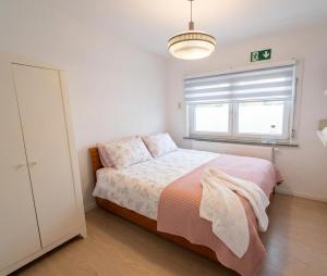 a white bedroom with a bed and a window at Negenendertigtwintig-Lommel in Lommel