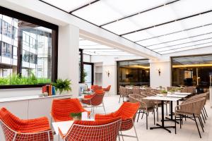 a restaurant with orange chairs and tables at Le Meridien Visconti Rome in Rome