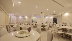 a dining room with tables and white chairs at Areen Almatar Serviced Apartments شقق ارين المطار للشقق المخدومة in Jeddah