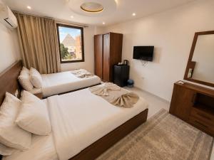 a hotel room with two beds and a television at Prince Pyramid HoteLL in Cairo