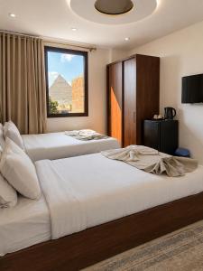 two beds in a hotel room with a window at Prince Pyramid HoteLL in Cairo