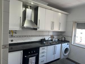 a kitchen with white cabinets and a sink and a washing machine at Renna in Corroios