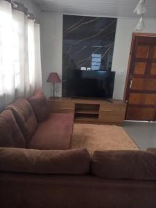 a living room with a couch and a flat screen tv at Casa proxima ABQM in Araçatuba +5 photos
