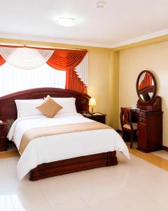 a bedroom with a bed and a desk and a mirror at Hotel Raices in Ambato