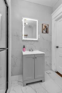 a white bathroom with a sink and a mirror at 4BR Apt Pool Table Sleeps 9 Buffalo in Buffalo +43 photos
