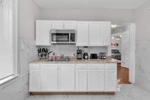 a white kitchen with a sink and a microwave at 4BR Apt Pool Table Sleeps 9 Buffalo in Buffalo