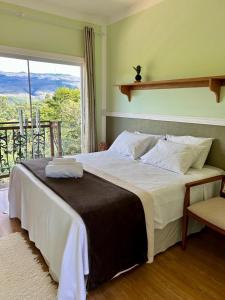 a bedroom with a large bed and a window at Pousada Canto do Luar in Conceição do Mato Dentro