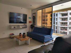 a living room with a blue couch and a tv at Apartamento Raúl Melendez Ámbar Villeta in Villeta