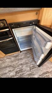 an empty refrigerator with its door open in a kitchen at Кемпер дом in Chişinău