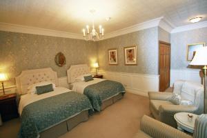 a bedroom with two beds and a chandelier at West Acre House in Alnwick