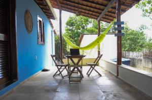 a porch with a table and chairs and a hammock at A Casa Azul in Barra Grande