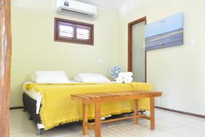 a bedroom with a bed with a yellow blanket and a bench at A Casa Azul in Barra Grande