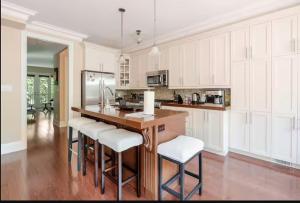 a kitchen with white cabinets and a wooden island with bar stools at Unique Home - Upper Toronto Beaches in Toronto