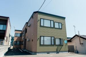 a yellow building with black windows on a street at ビアンカ Bianca A号室 in Asahikawa