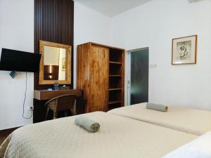 a bedroom with two beds and a desk and a mirror at Ashana Hotel in Uluwatu
