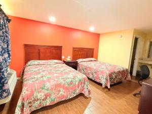 two beds in a room with orange walls at Budget Inn in Vidalia