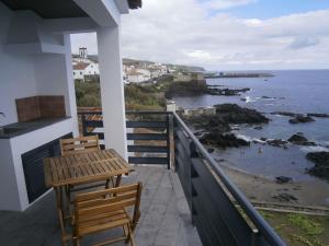 a balcony with two chairs and a table and the ocean at Casa Das Dias in Vila Franca do Campo