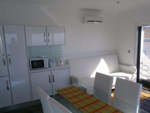 a kitchen with a glass table and white chairs at Casa Das Dias in Vila Franca do Campo +16 photos