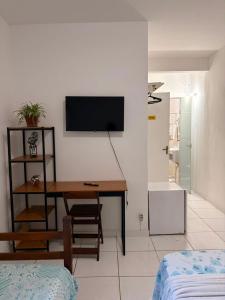 a room with a desk and a tv on a wall at Caminho das Pedras Búzios in Búzios