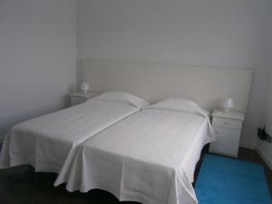 a bedroom with a white bed with a blue carpet at Casa Das Dias in Vila Franca do Campo