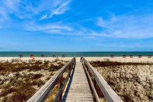 a wooden boardwalk leading to the beach with umbrellas at Spacious Condo with full kitchen shared pool and beach access in Perdido Key
