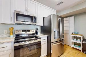 a kitchen with white cabinets and a stainless steel refrigerator at Spacious Condo with full kitchen shared pool and beach access in Perdido Key +10 photos